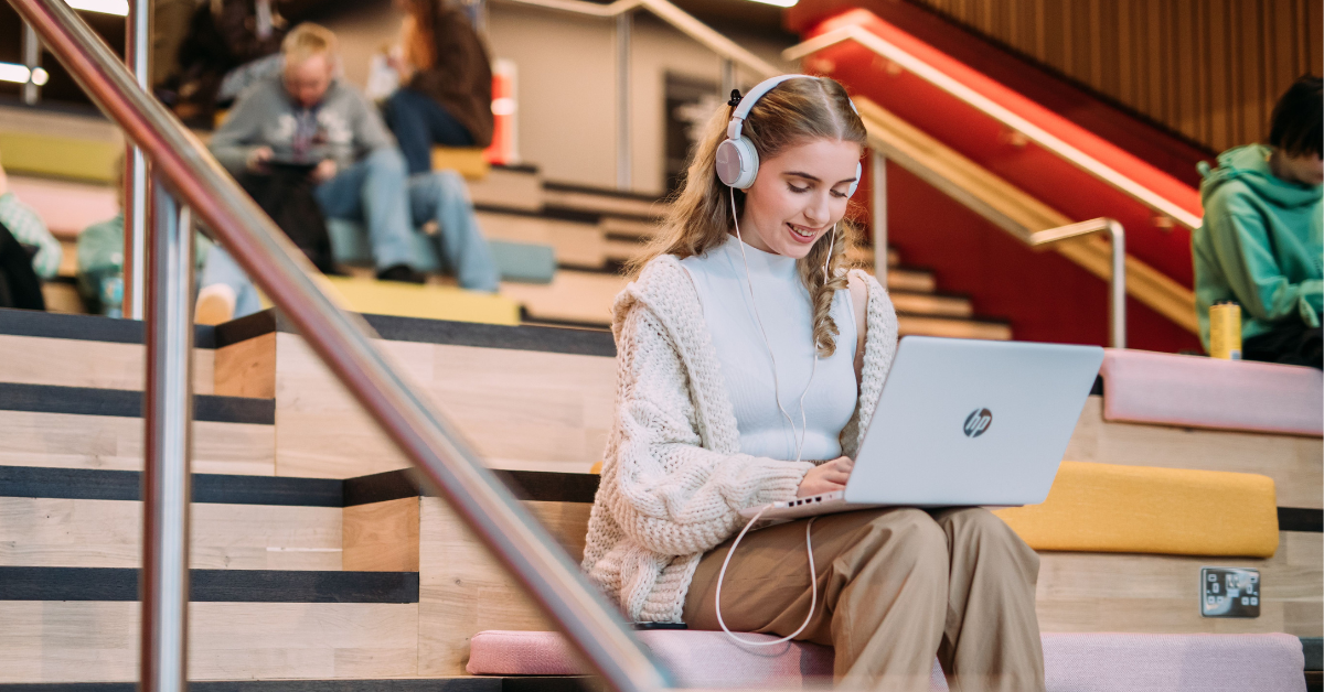 Queen's student on laptop in One Elmwood staircase