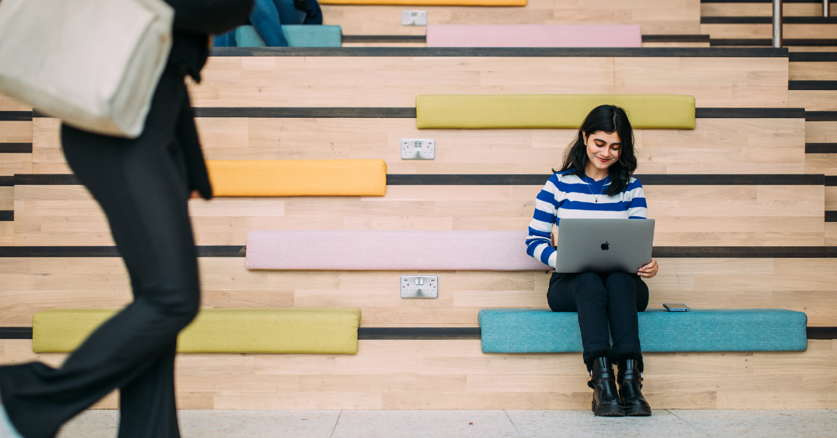 Queen's student on laptop on social staircase in One Elmwood