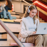 Queen's student on laptop in One Elmwood staircase
