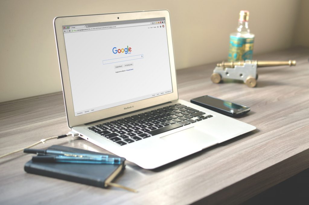 Photo of a laptop open on a desk, with a Google search page on the screen.