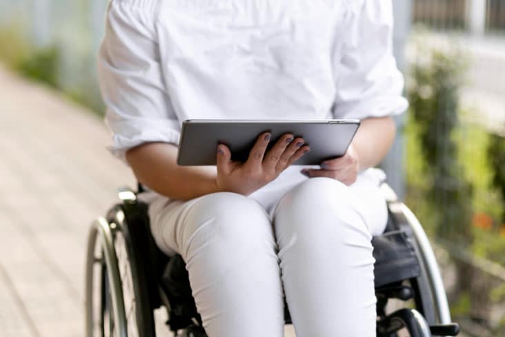 A person using a wheelchair and holding a tablet device