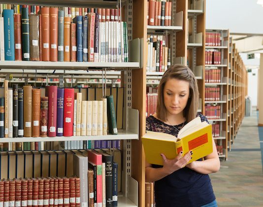 photo of woman reading book in McClay library