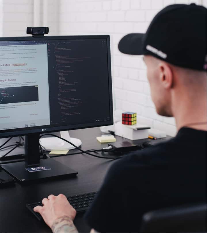 Man working at a desktop computer with code on screen