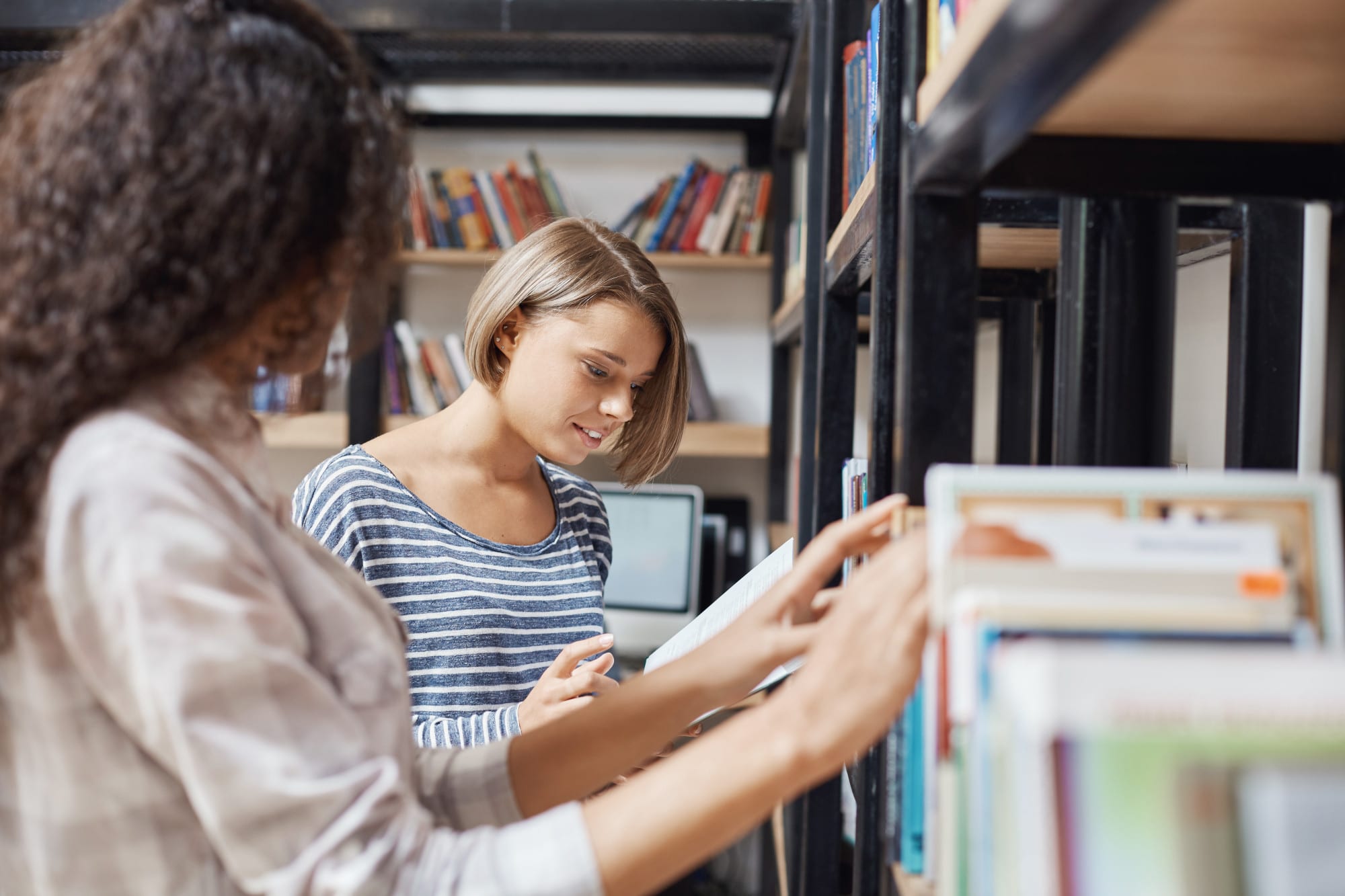 Two young women looking for books in a library