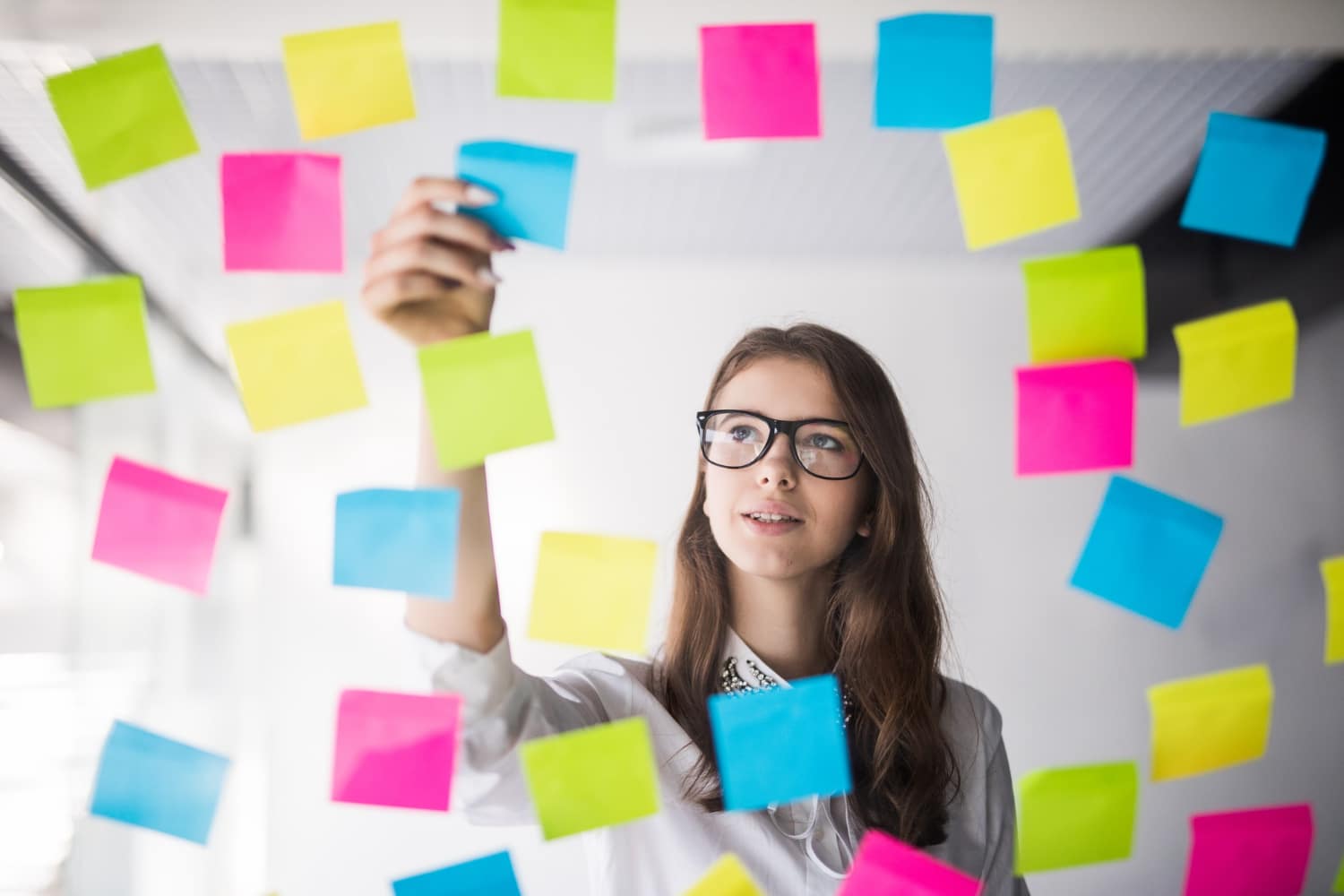 Woman placing sticky notes onto a wall