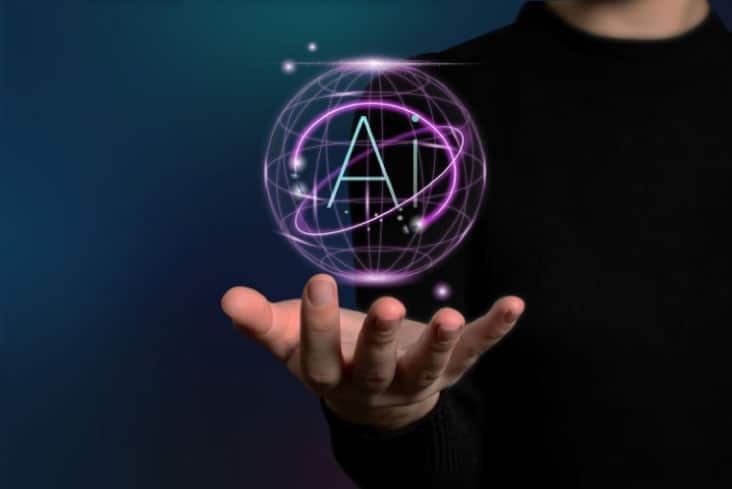 Human hand holding a futuristic hologram ball containing the letters AI