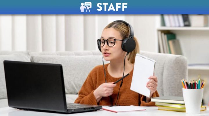 Woman with headphones holding a book while on a video call