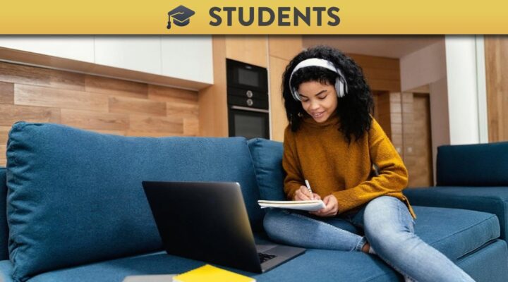 Student watching lecture recording and taking notes