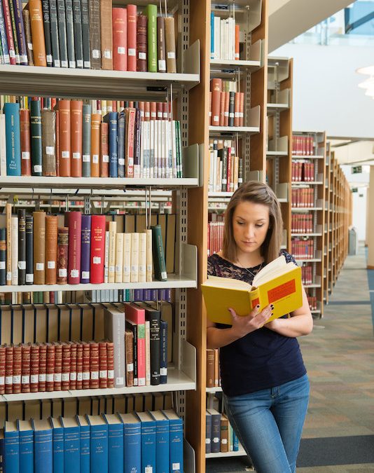 photo of woman reading book in McClay library