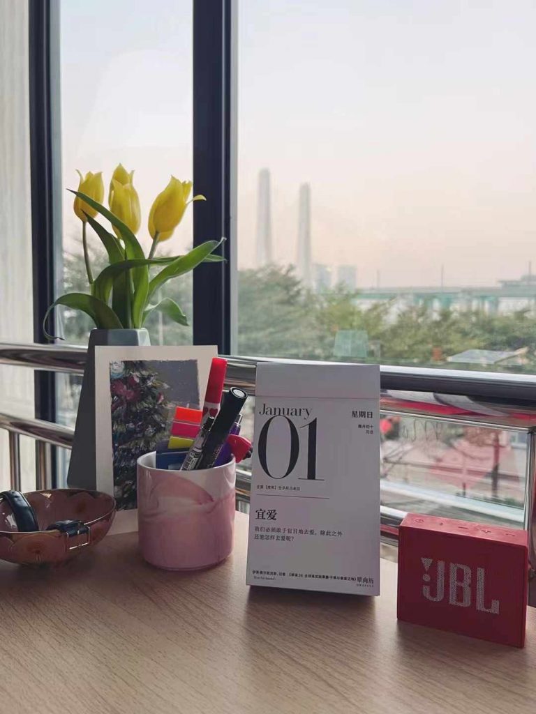 A calendar on a desk, displaying January 1st 2023, together with some other stationery and a flower vase with some tulips.