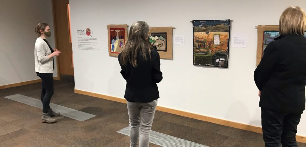 People viewing Conflict textiles exhibition at the McClay Library. 