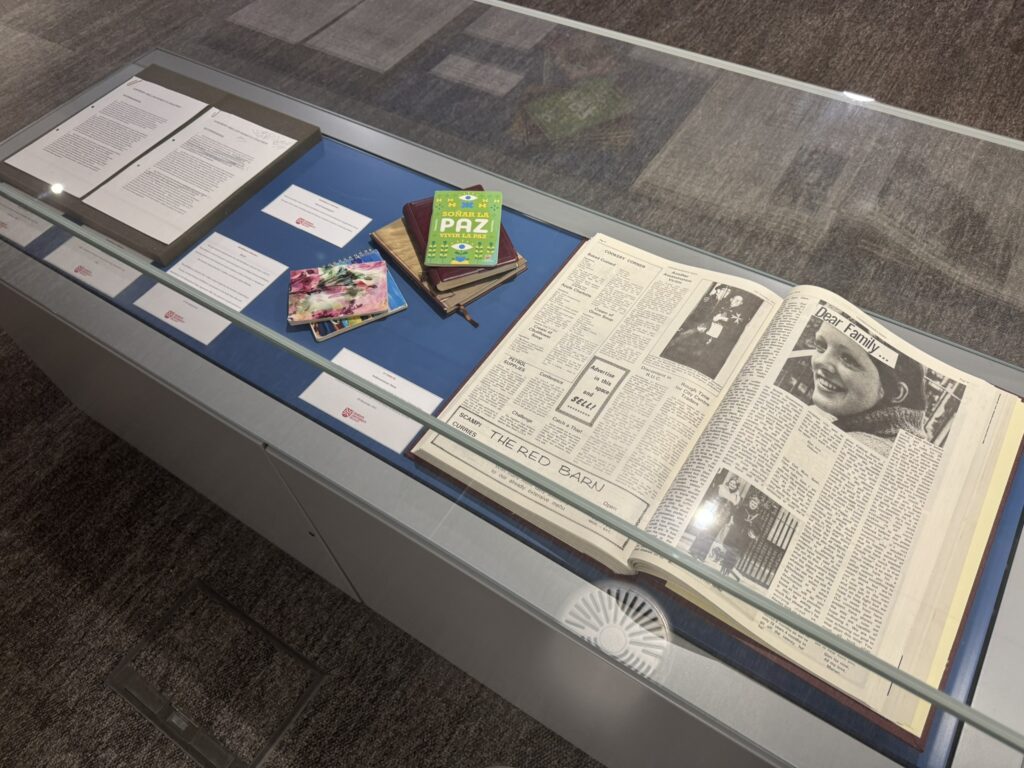 Display case featuring items from the McWilliams Collection and a bound volume of the Andersonstown News.